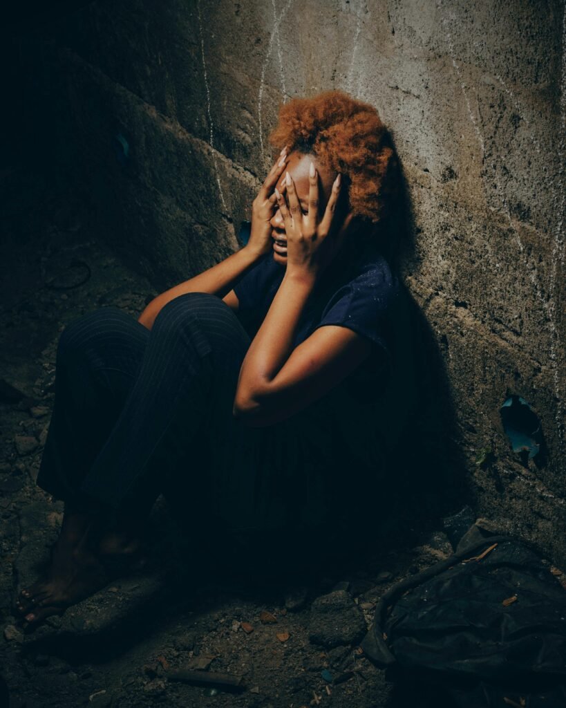 A woman in a dark street covering her eyes with her hands and crying over emotional breakdown