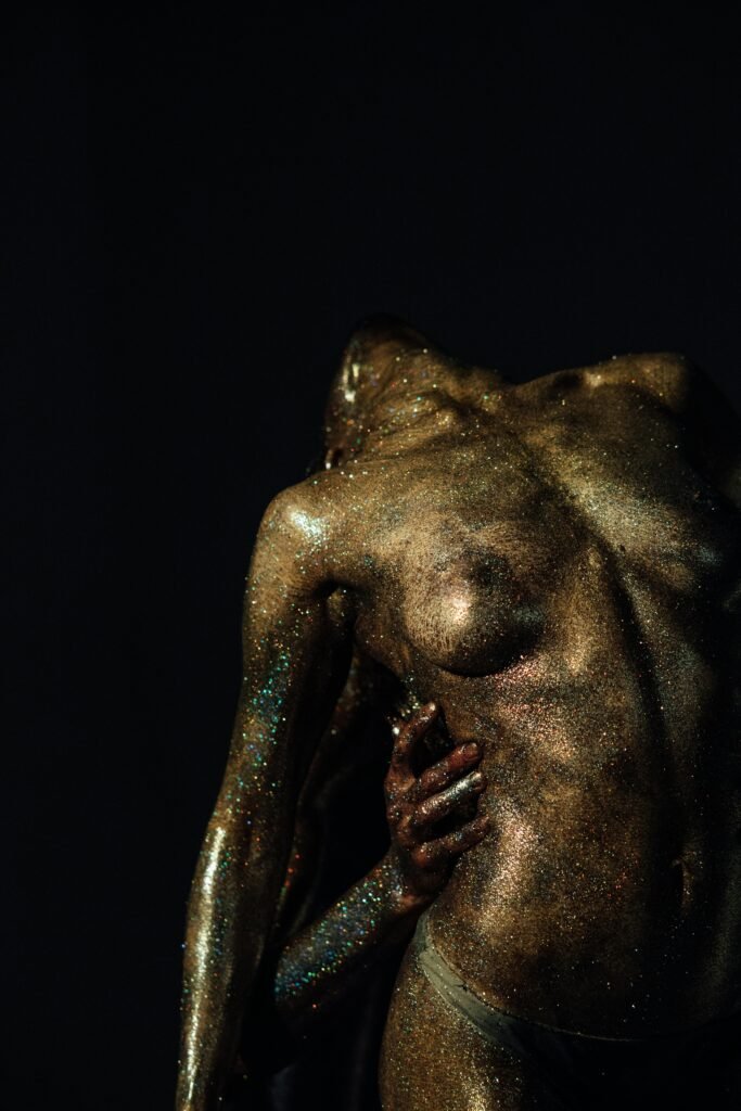 artistic image of two bodies covered in glitter touching and supporting each other.