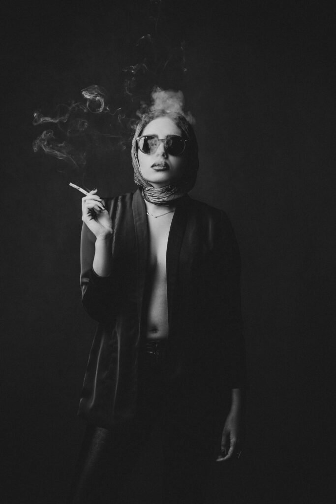 a woman smoking a cigarette wearing provocative shirt, a scarf on the head and dark sunglasses